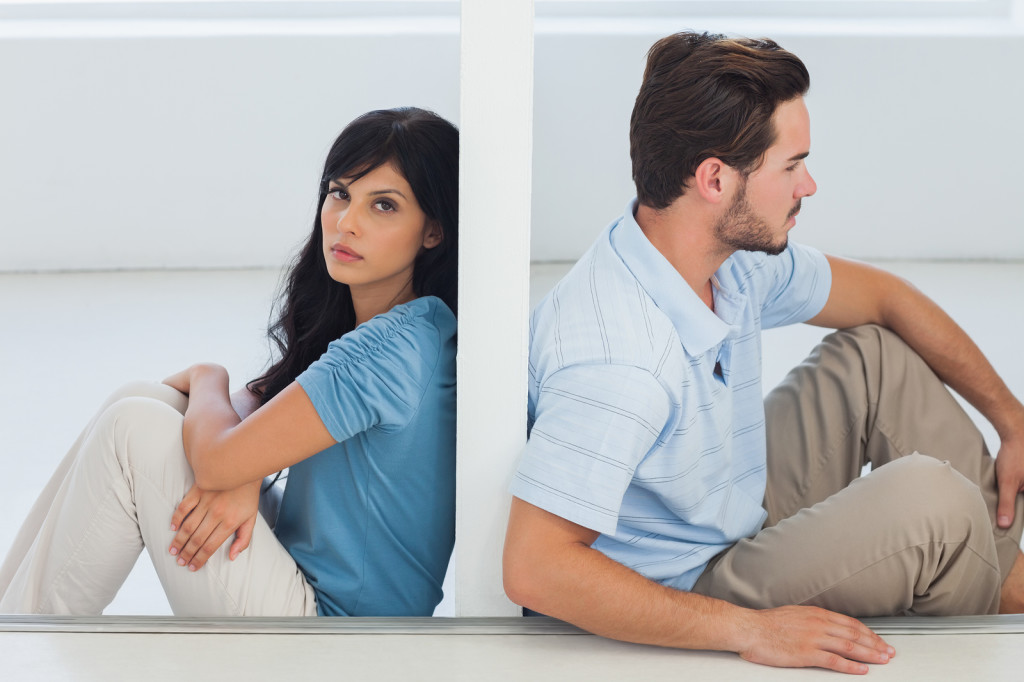 Sitting couple are separated by wall with woman looking at camer